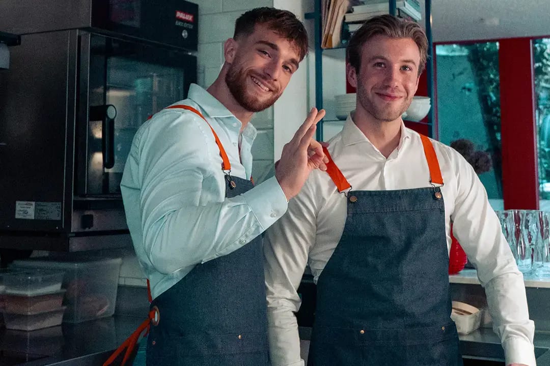 Een vrolijke gast die hardop lacht om een grappige tekst op een opengeslagen drankkaart aan de bar.